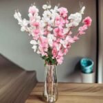 Artificial cherry blossom flowers in pink and white displayed in a clear glass vase for interior decoration