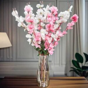 Artificial cherry blossom flowers in red and pink and whitedisplayed in a clear glass vase for interior decoration