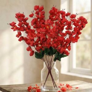 Artificial cherry blossom flowers in red displayed in a clear glass vase for interior decoration.