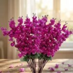 Artificial cherry blossom flowers in red and purple displayed in a clear glass vase for interior decoration