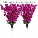 Artificial cherry blossom flowers in purple displayed in a clear glass vase for interior decoration.