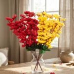 Artificial cherry blossom flowers in red and yellow displayed in a clear glass vase for interior decoration