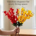 Artificial cherry blossom flowers in red and yellow displayed in a clear glass vase for interior decoration