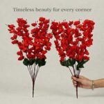 Artificial cherry blossom flowers in red and red displayed in a clear glass vase for interior decoration